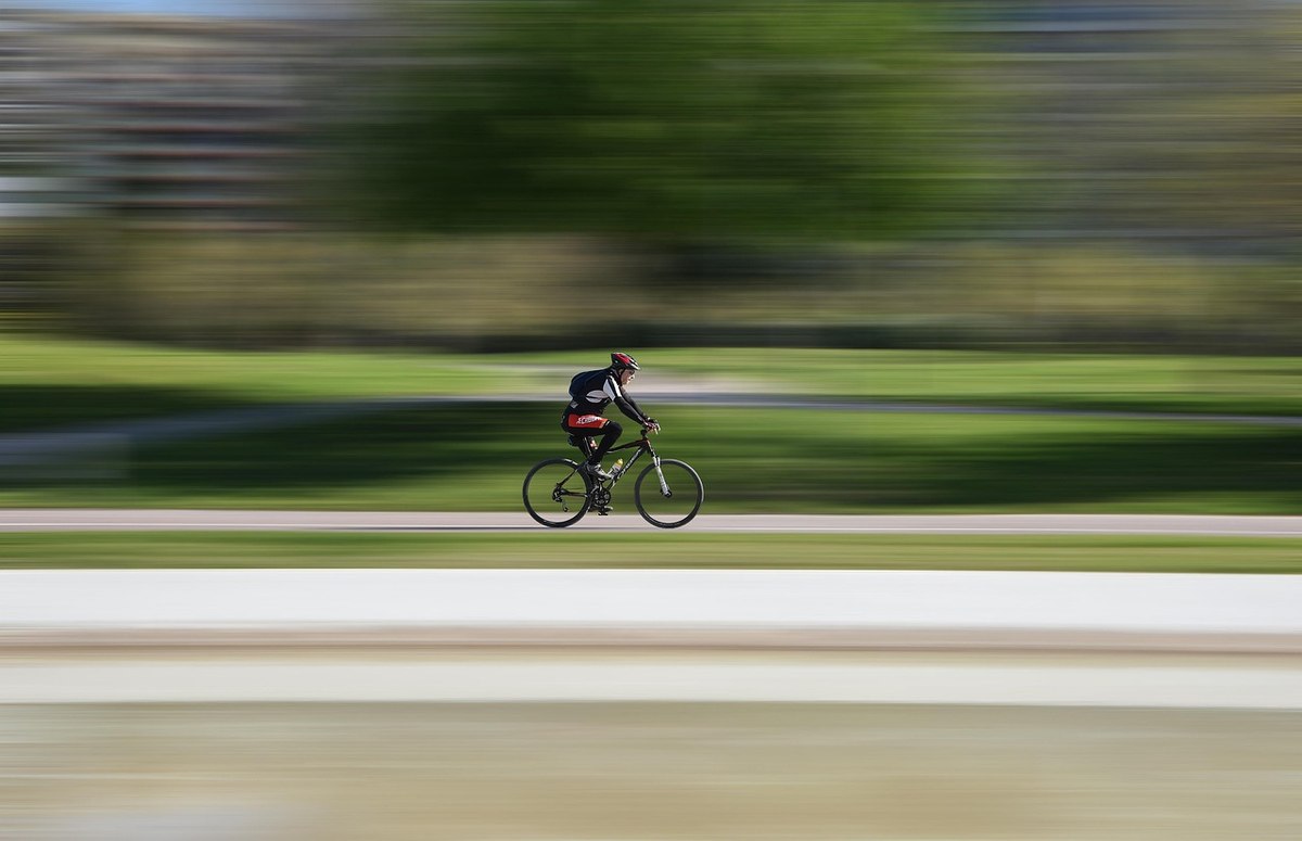 Cycliste roulant rapidement sur une route avec paysage verdoyant flou en arrière-plan