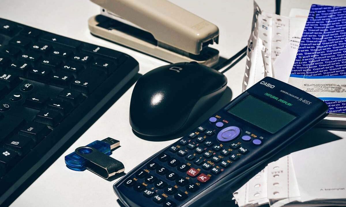 Clavier, souris, calculatrice, agrafeuse, clé USB, papiers sur un bureau