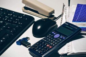Clavier, souris, calculatrice, agrafeuse, clé USB, papiers sur un bureau