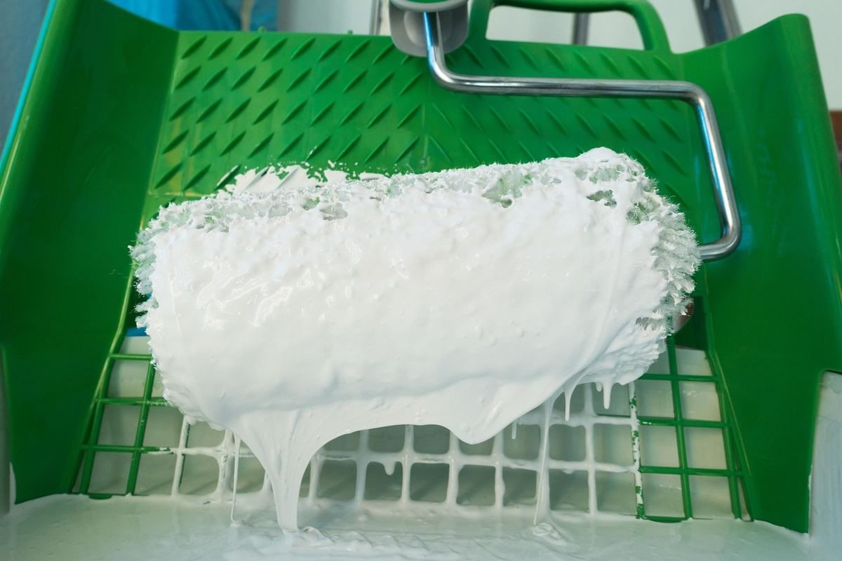 Rouleau de peinture chargé dans bac vert peinture blanche s'écoule Rouleau de peinture chargé dans bac vert peinture blanche s'écoule