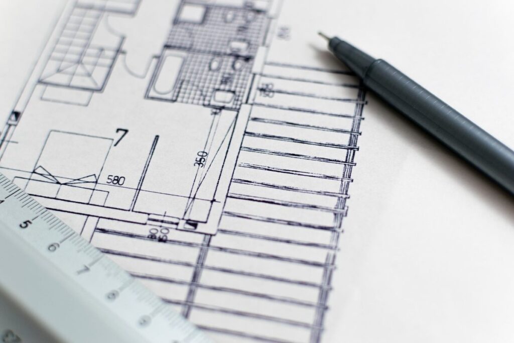 Feuille de plan, stylo et règle posés sur papier blanc