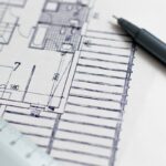 Feuille de plan, stylo et règle posés sur papier blanc