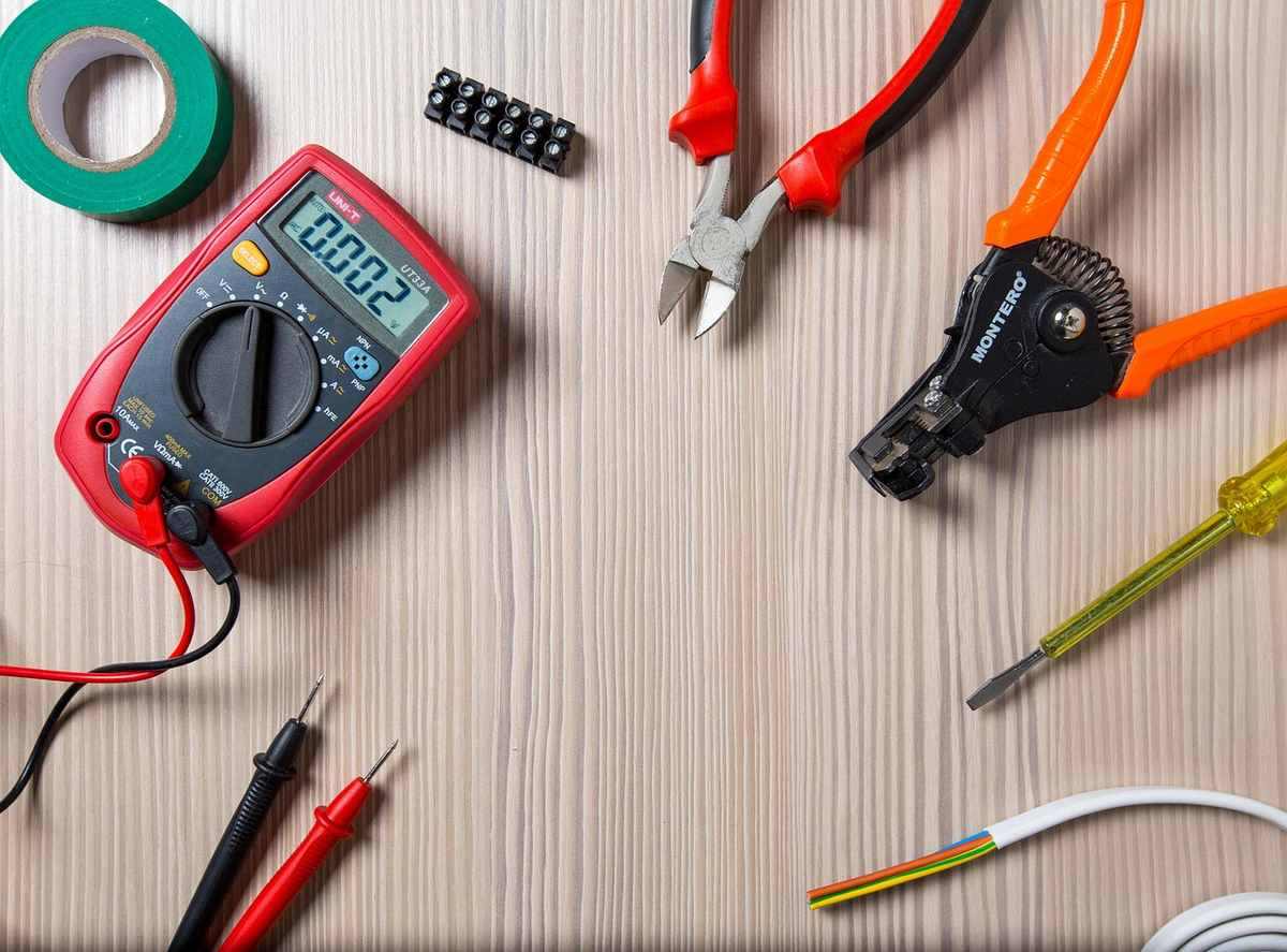 Outils de bricolage sur une table, incluant un multimètre, des pinces et un tournevis Outils de bricolage sur une table, incluant un multimètre, des pinces et un tournevis